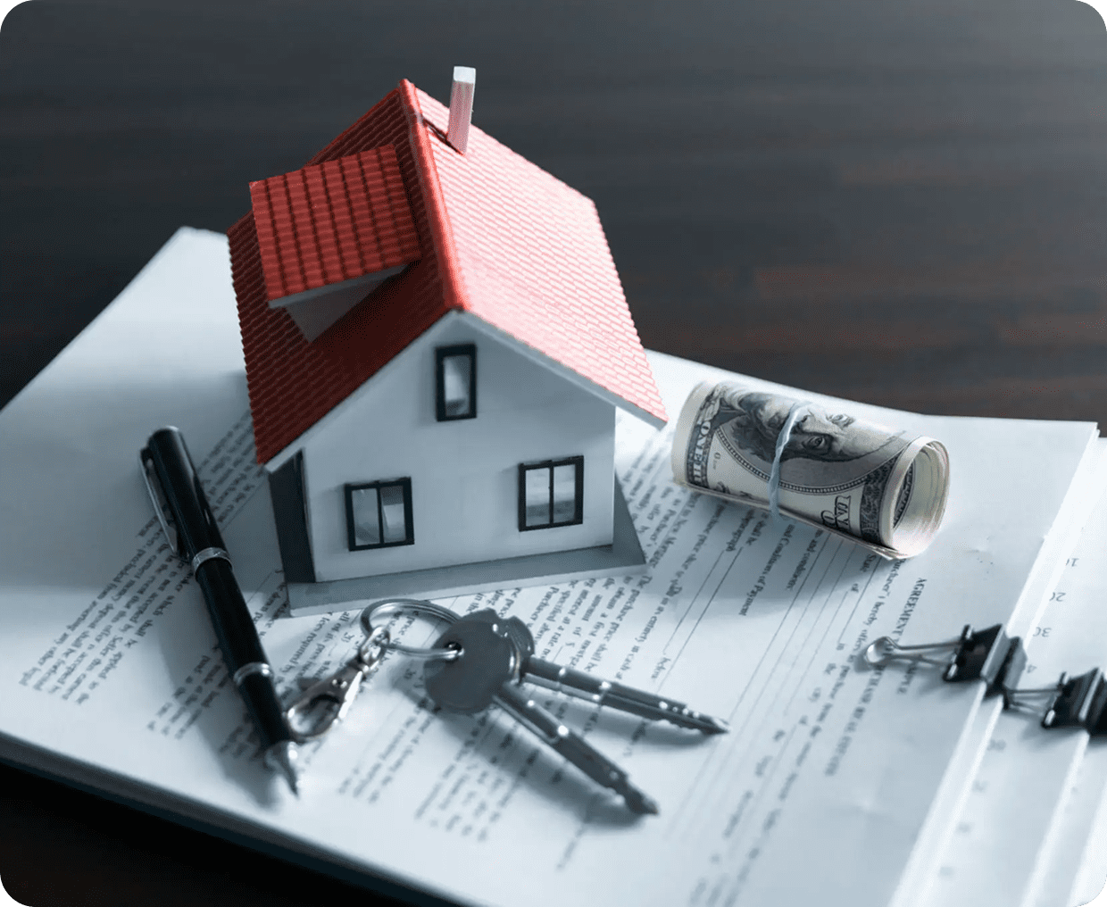A miniature house model on a stack of paperwork